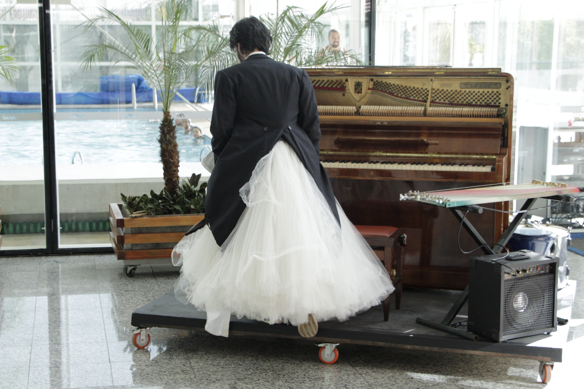 Foto homem de vestido de noiva e terno em tablado com piano e teclado