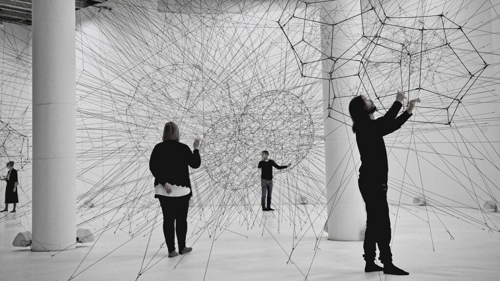 Pesoas em exposição de arte com redes de fios conectados