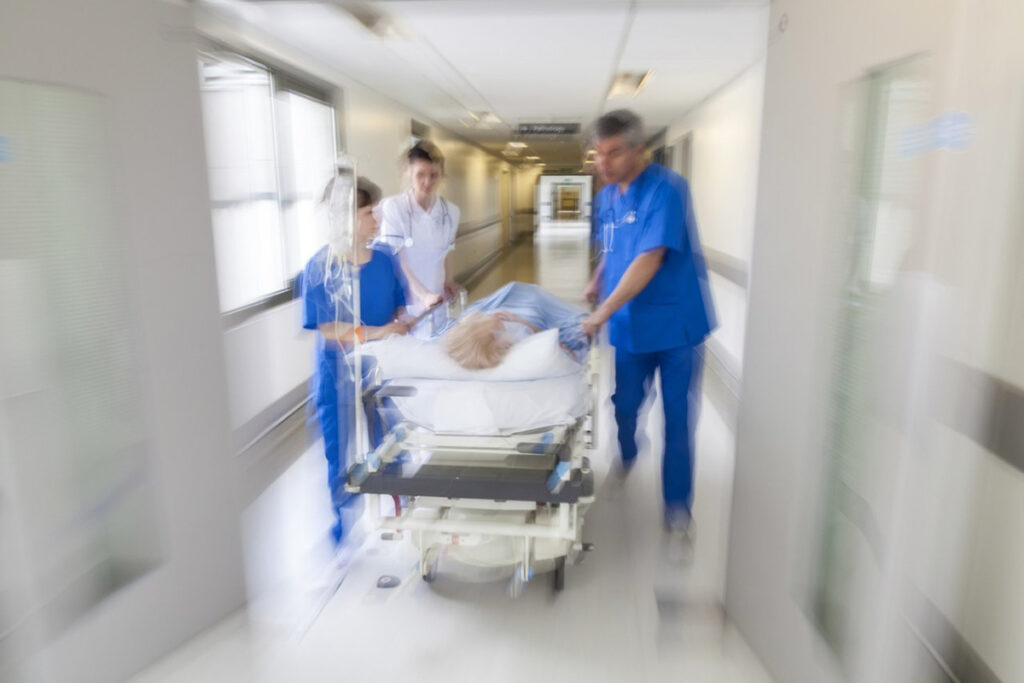 Corredor de hospital com pessoas correndo com uma maca