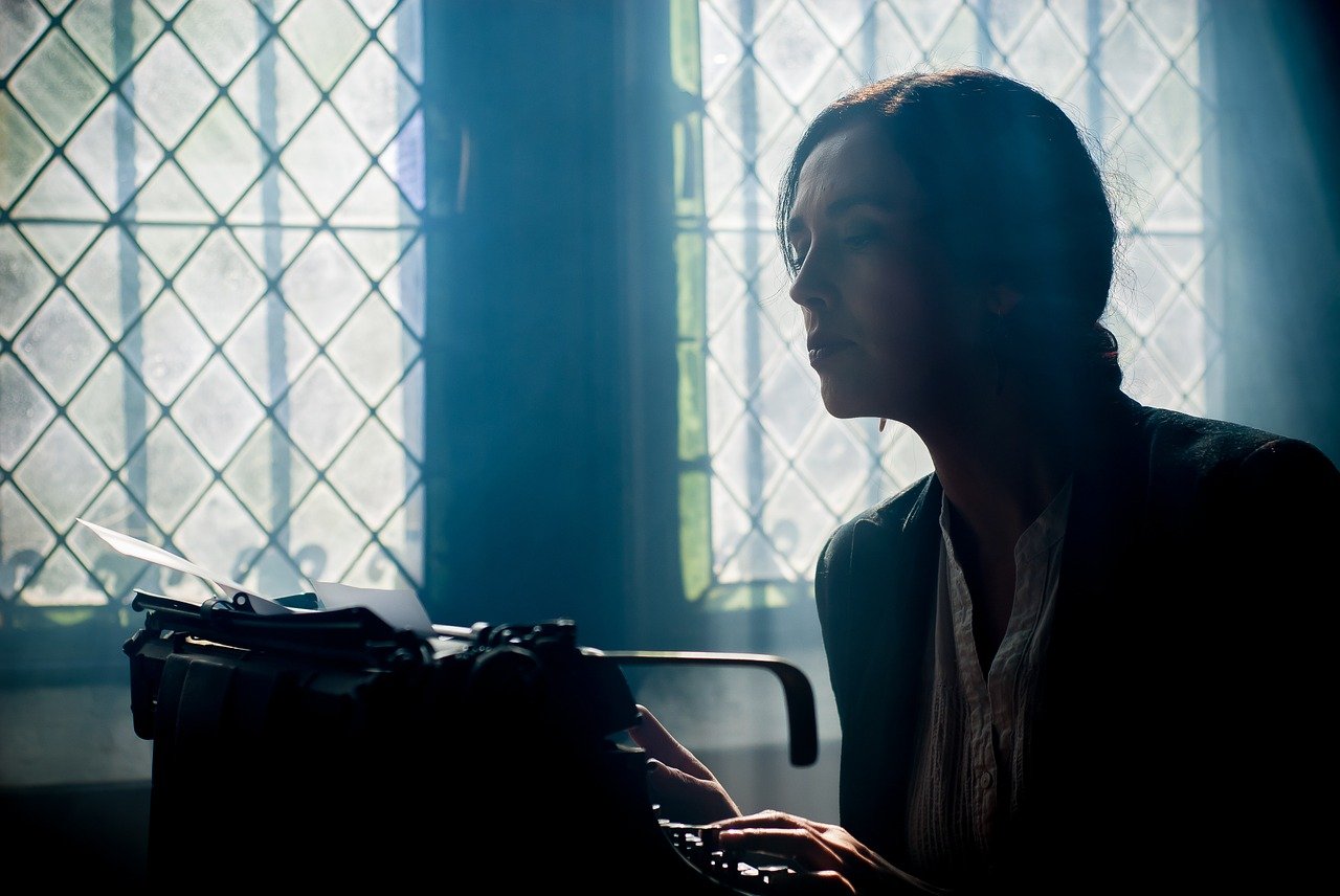 Escritora escrevendo em máquina de escrever, na penumbra