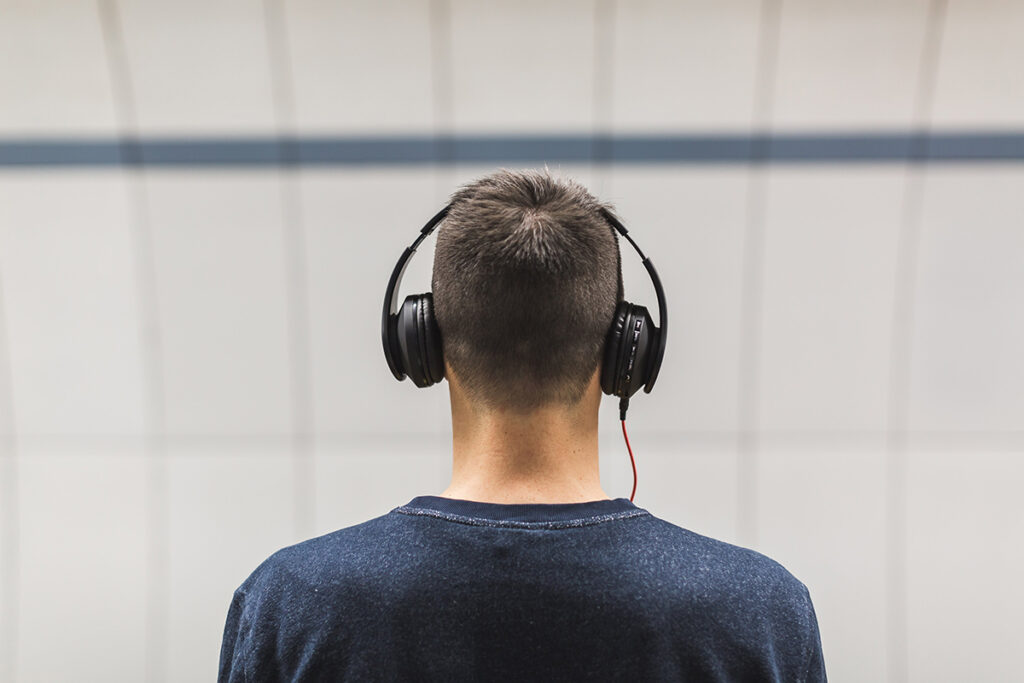 Homem de costas com headphone na cabeça. Imagem: Rawpixel CC